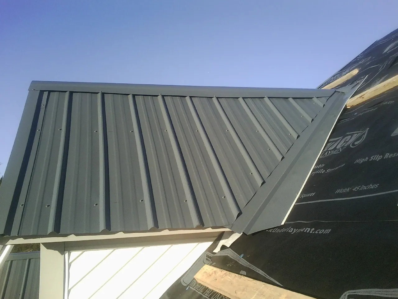 Gray metal roof panels going on over a garage gable in Harker Heights