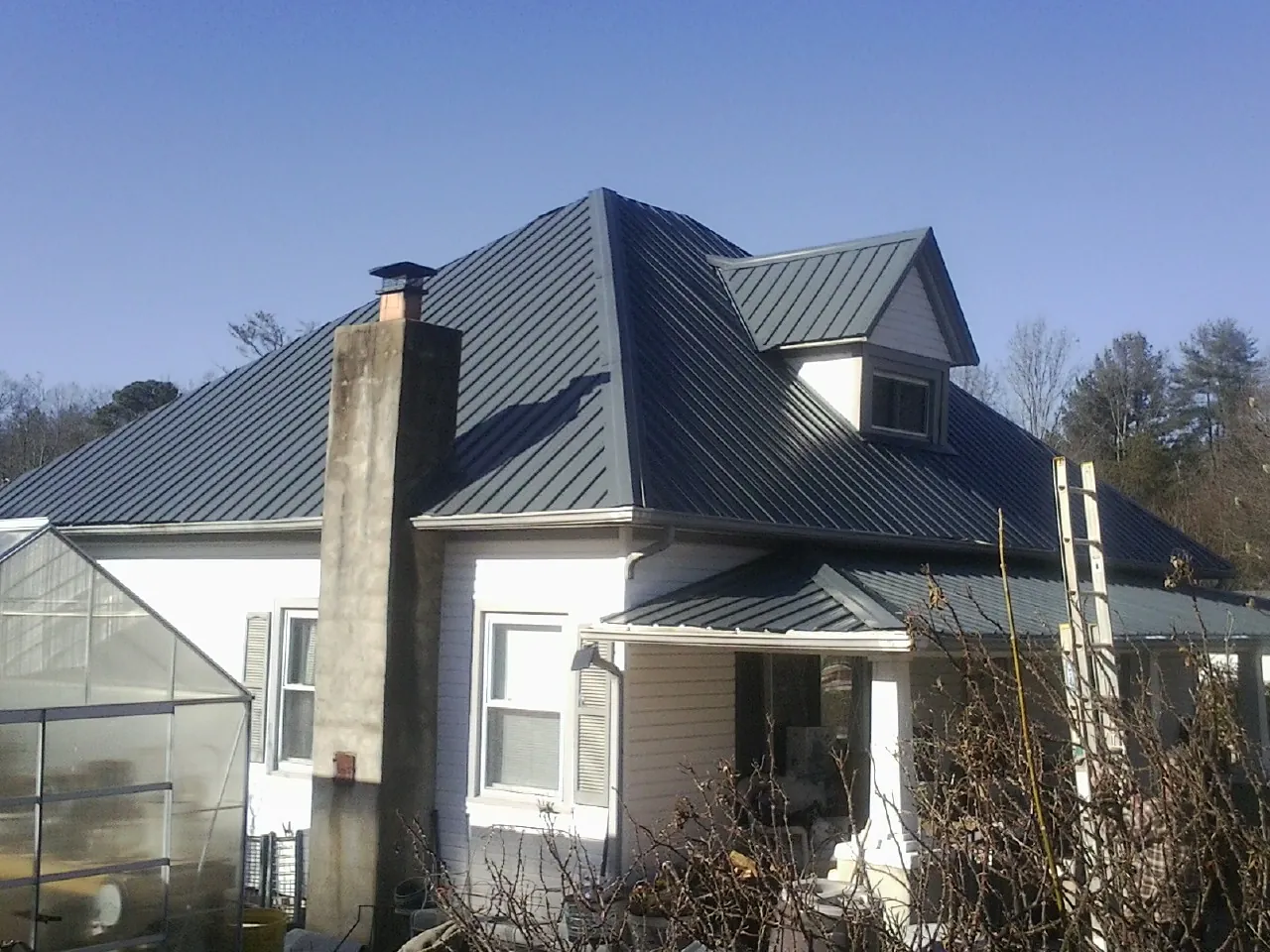 Dark blue standing seam metal roof on a white farmhouse with dormer — Slate & Tile Roof Repair by Roofing Brothers in Harker Heights