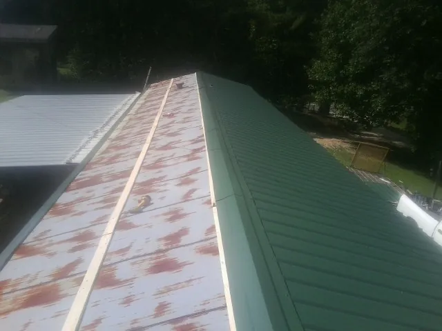 Old rusted panels beside newly installed green metal roofing — Wind Damage Roof Repair by Roofing Brothers in Harker Heights