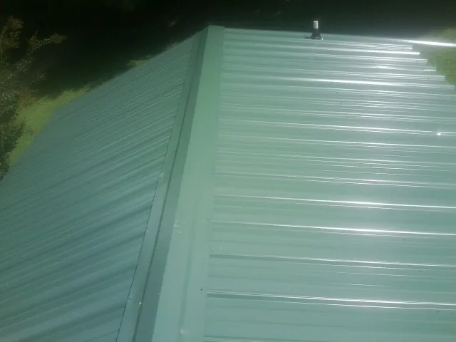 New green metal panels meeting at the ridge of a roof — Flat Roof Repair work by our crew in Harker Heights