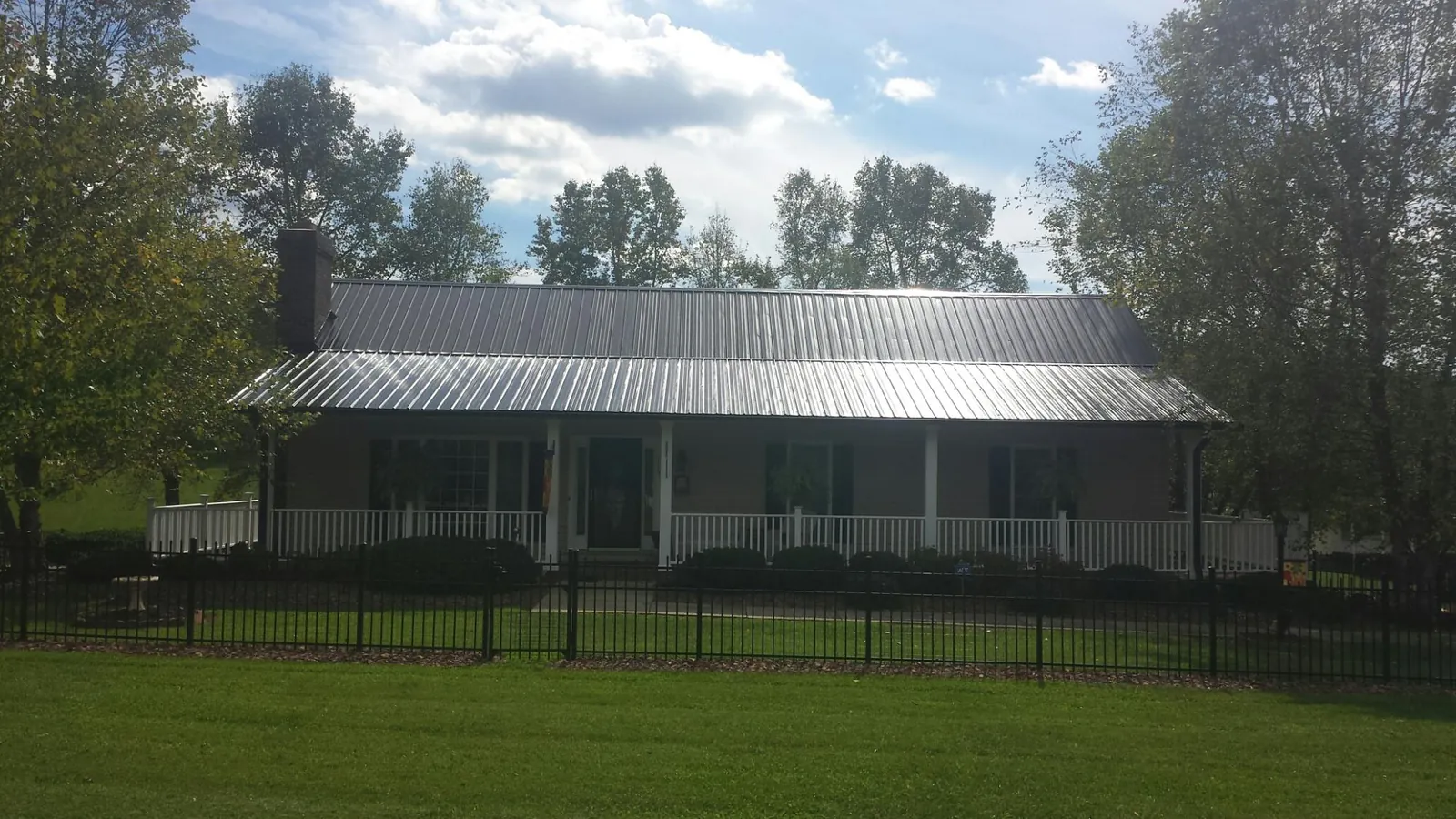 Gray metal roof on a brick ranch with a full width front porch — Gutter Guard Installation work by our crew in Harker Heights