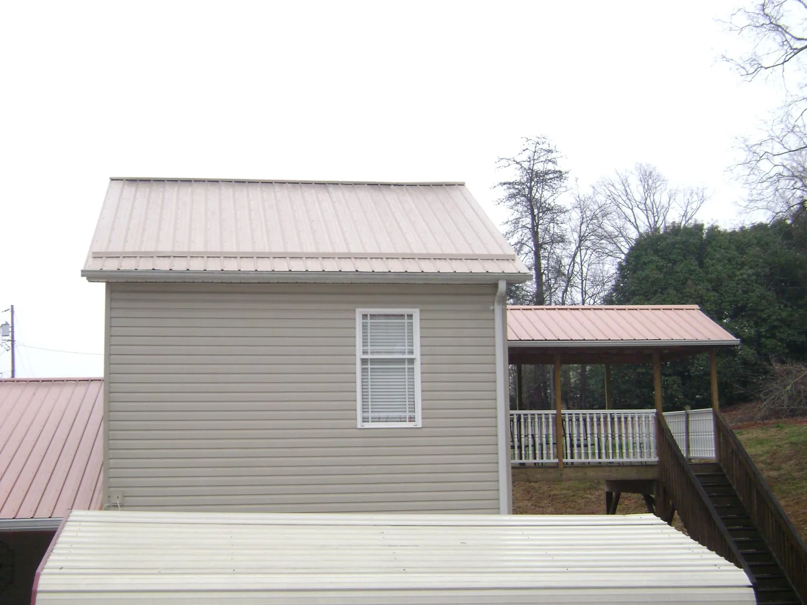 Tan metal roofs on a two story addition and attached porch, from a Roof Replacement job in Harker Heights