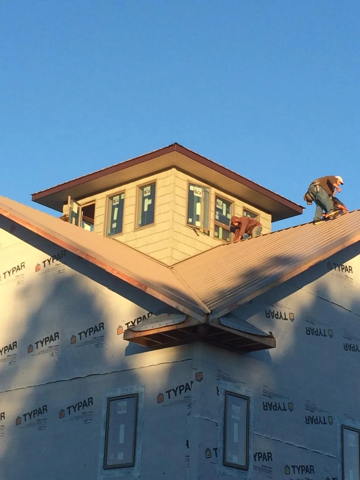 Roofers working around a rooftop cupola on a new metal roof at sunset — Roof Waterproofing in Harker Heights by Roofing Brothers